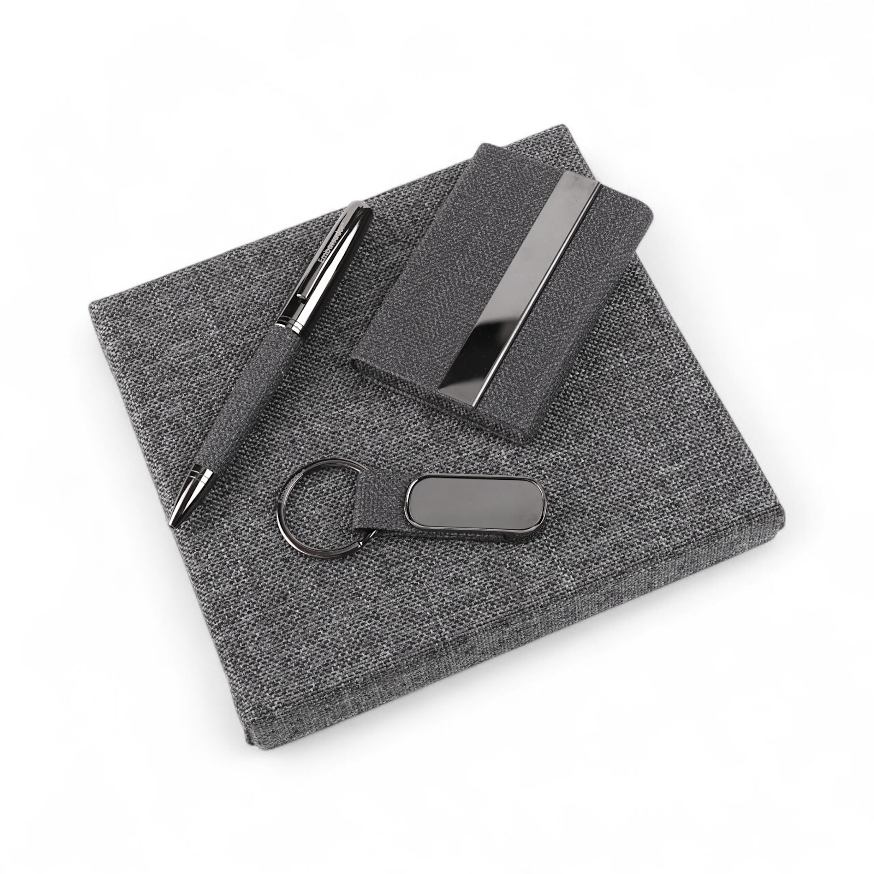 Minimalist stationery items including pen, notebook, and accessories on grey fabric